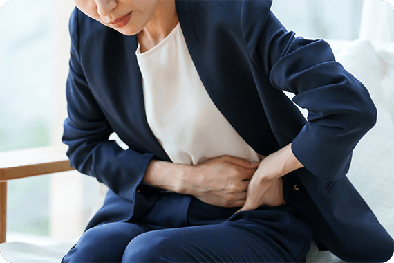 お腹を押さえて腹痛に耐える女性のイメージ